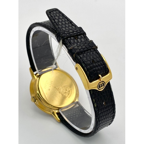 268 - An iconic GUCCI watch with original lizard skin strap. Case: 33 mm, red/blue dial with gold coloured... 