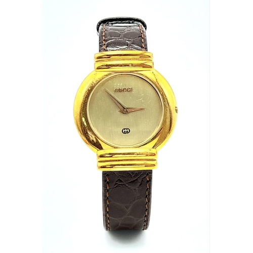 275 - A gold plated GUCCI with crocodile skin strap, case: 33 mm, gold coloured dial and hands, Swiss made... 