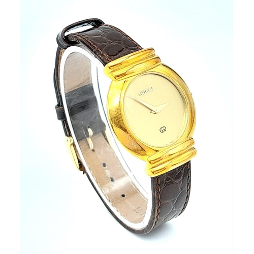 275 - A gold plated GUCCI with crocodile skin strap, case: 33 mm, gold coloured dial and hands, Swiss made... 