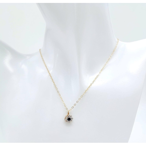 50 - An elegant 9 K yellow gold pendant with a blue sapphire surrounded by a halo of round cut diamonds o... 