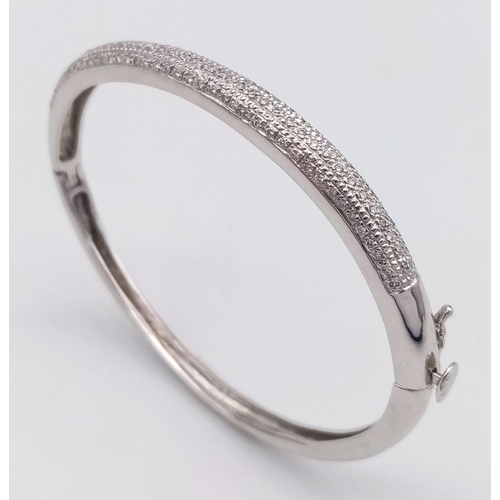 61 - A PRETTY 9K WHITE GOLD DIAMOND SET BANGLE WITH APPROX 0.60CT DIAMONDS IN TOTAL, WITH SAFETY CATCH AT... 