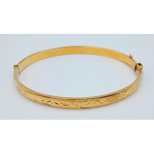 71 - A 9 K yellow gold bangle with a decorative engraving on top half, weight: 12.4g