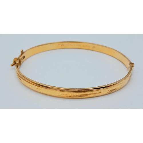 71 - A 9 K yellow gold bangle with a decorative engraving on top half, weight: 12.4g