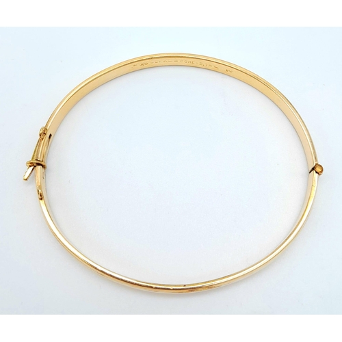 71 - A 9 K yellow gold bangle with a decorative engraving on top half, weight: 12.4g