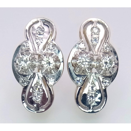 9 - An 18 K white and yellow gold pair of earrings with a nice, diamond set design, length: 21 mm, weigh... 