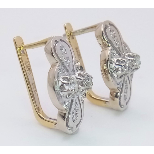 9 - An 18 K white and yellow gold pair of earrings with a nice, diamond set design, length: 21 mm, weigh... 