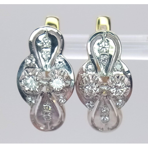 9 - An 18 K white and yellow gold pair of earrings with a nice, diamond set design, length: 21 mm, weigh... 