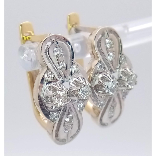 9 - An 18 K white and yellow gold pair of earrings with a nice, diamond set design, length: 21 mm, weigh... 