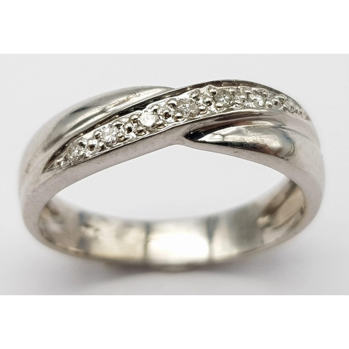 453 - A 9K white Gold (tested) Diamond Twist Ring. 0.05ct diamond. Size K. 2.4g total weight.