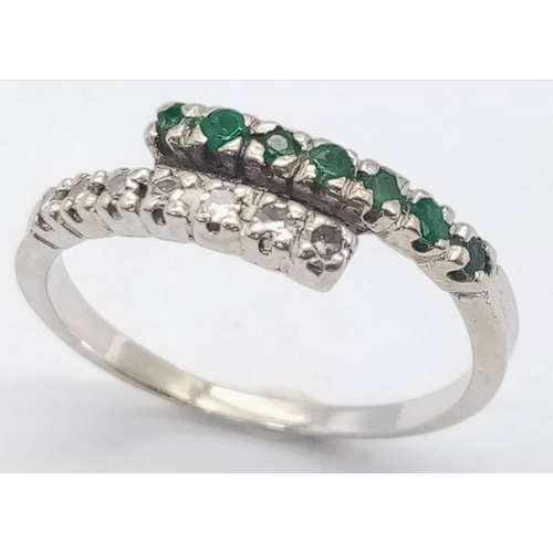 379 - An 18 K white gold ring with one emerald band and one diamond band crossing over, size: L, weight: 1... 