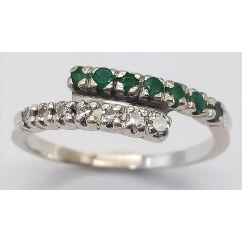 379 - An 18 K white gold ring with one emerald band and one diamond band crossing over, size: L, weight: 1... 