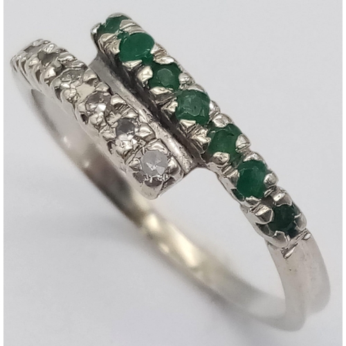 379 - An 18 K white gold ring with one emerald band and one diamond band crossing over, size: L, weight: 1... 