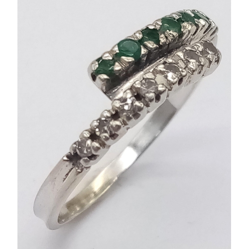 379 - An 18 K white gold ring with one emerald band and one diamond band crossing over, size: L, weight: 1... 