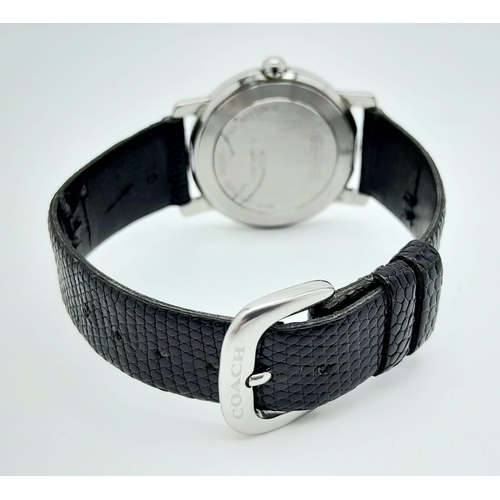 529 - A Coach Quartz Gents Watch. Black leather strap. Stainless steel case. White dial. In working order.