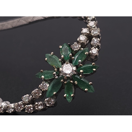 144 - An 18K White Gold Diamond and Emerald Necklace. A scale pattern necklace that leads to an emerald fl... 