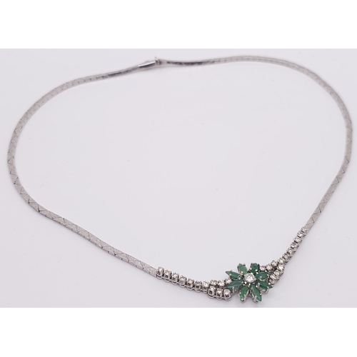 144 - An 18K White Gold Diamond and Emerald Necklace. A scale pattern necklace that leads to an emerald fl... 