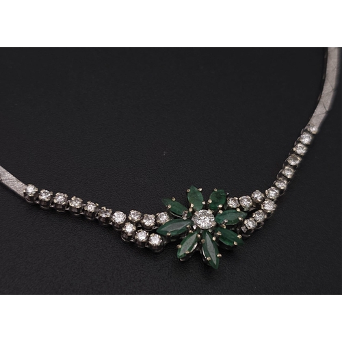 144 - An 18K White Gold Diamond and Emerald Necklace. A scale pattern necklace that leads to an emerald fl... 