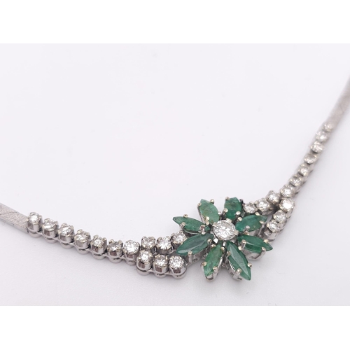 144 - An 18K White Gold Diamond and Emerald Necklace. A scale pattern necklace that leads to an emerald fl... 