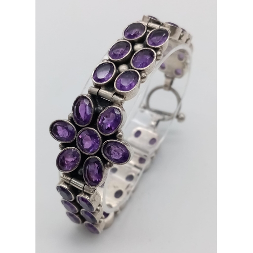 209 - An Amethyst Tennis Bracelet set in 925 Sterling silver. Two rows of oval cut amethysts meet a centra... 