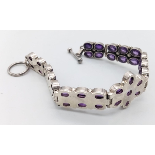 209 - An Amethyst Tennis Bracelet set in 925 Sterling silver. Two rows of oval cut amethysts meet a centra... 