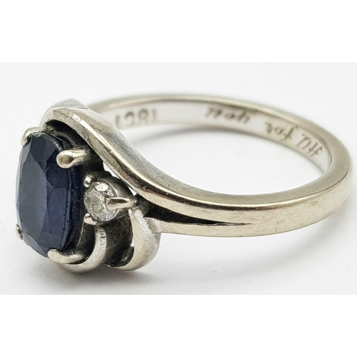 598 - an 18k white gold ring with central sapphire and flanked by 2 small diamonds  . 4.4GMS   size K