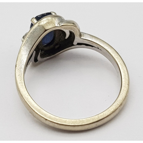 598 - an 18k white gold ring with central sapphire and flanked by 2 small diamonds  . 4.4GMS   size K