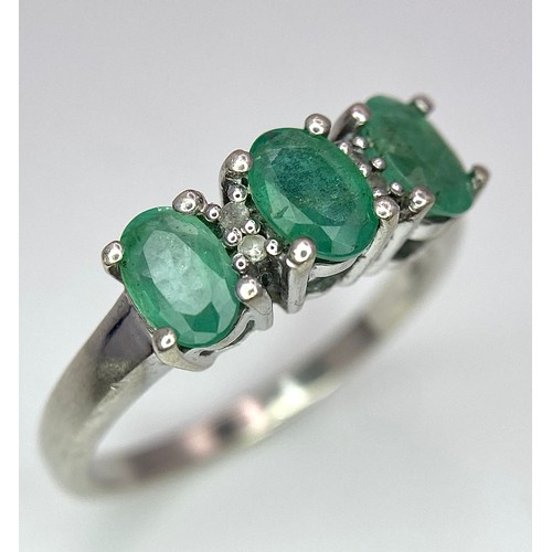 888 - A Sterling Silver Three Emerald and Four Diamond Ring Size P. Set three oval cut 7mm Emeralds and fo... 