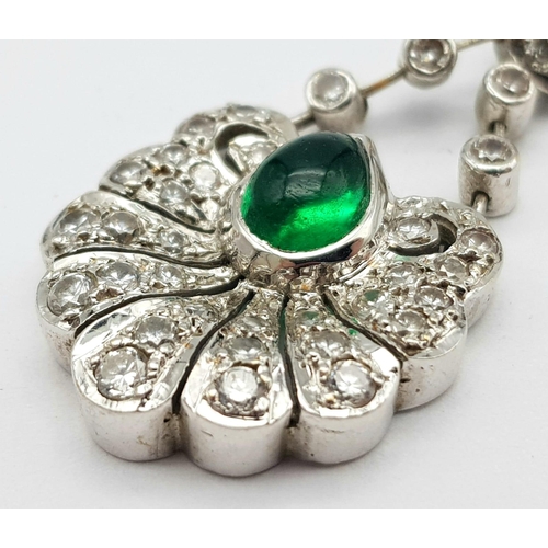 723 - An 18K White Gold Emerald and Diamond Pendant. Central teardrop emerald with a white diamond petal c... 