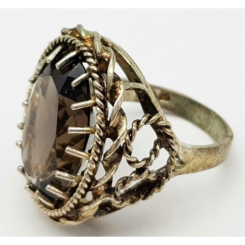 71 - A vintage large smoky quartz faceted stone set ring on crown mount, with lovely scroll work on shoul... 