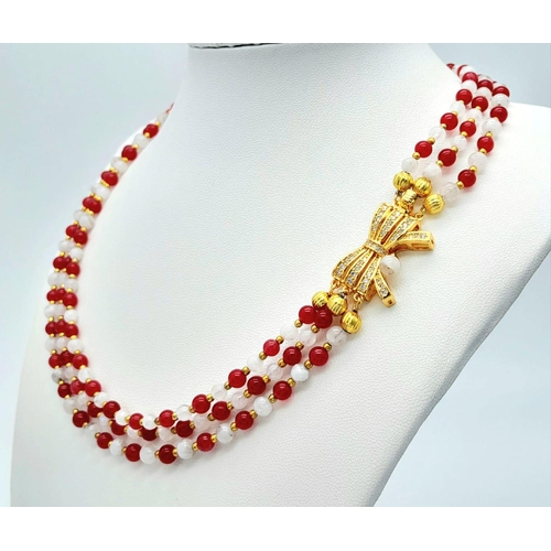 207 - A very elegant, three row necklace with alternating rubies and moonstones, adorned with an ornamenta... 