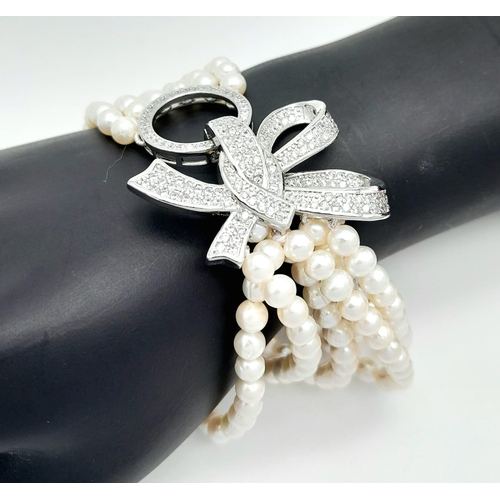 270 - A fabulous six strand natural pearl bracelet with a large bow shaped clasp adorned with dozens of cu... 