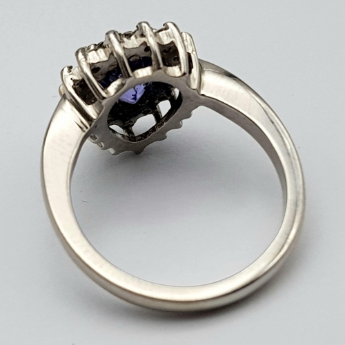 109 - An 18 K white gold ring with a pear cut tanzanite (1.71 carats) surrounded by a halo of diamonds, ri... 