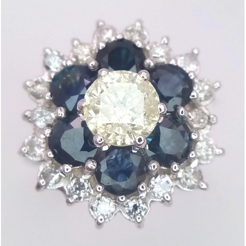 113 - An 18K White Gold Diamond and Sapphire Ring. Central tinted 1ct diamond with sapphire and white diam... 