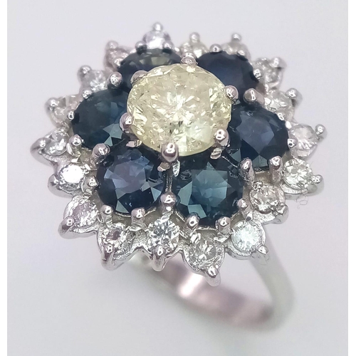 113 - An 18K White Gold Diamond and Sapphire Ring. Central tinted 1ct diamond with sapphire and white diam... 