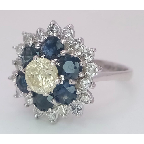 113 - An 18K White Gold Diamond and Sapphire Ring. Central tinted 1ct diamond with sapphire and white diam... 