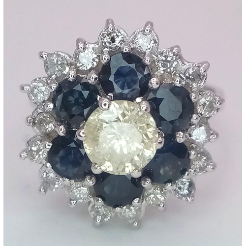 113 - An 18K White Gold Diamond and Sapphire Ring. Central tinted 1ct diamond with sapphire and white diam... 