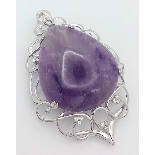 186 - A 9 K white gold pendant with a large pear shaped amethyst cabochon (80.36 carats) set on an ART NOU... 