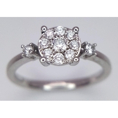 261 - A 9 K white gold ring with a diamond cluster and a single diamond at the top of each shoulder, size:... 