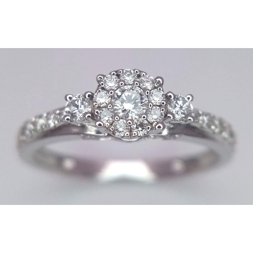 318 - A 9 K white gold ring with a diamond cluster and more diamonds on the shoulders (total 0.41 carats),... 