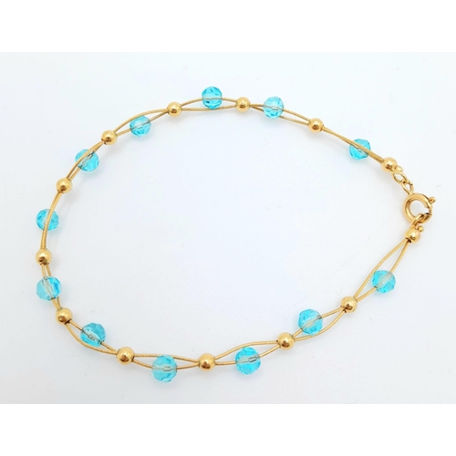 458 - An unusual 18 K yellow gold bracelet with two gold wires carrying alternating blue crystal faceted b... 