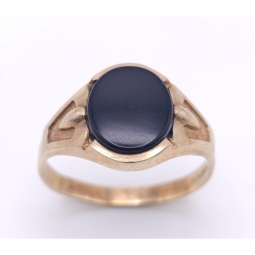 192 - A GENTS 9K GOLD OVAL BLACK ONYX RING WITH DECORATIVE SHOULDERS .   2.8gms   size U