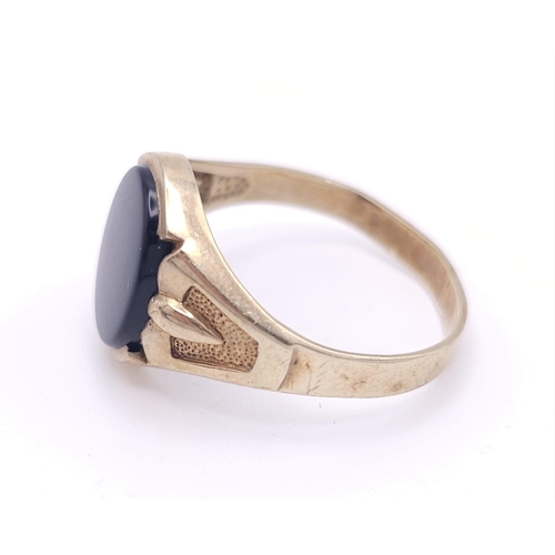 192 - A GENTS 9K GOLD OVAL BLACK ONYX RING WITH DECORATIVE SHOULDERS .   2.8gms   size U