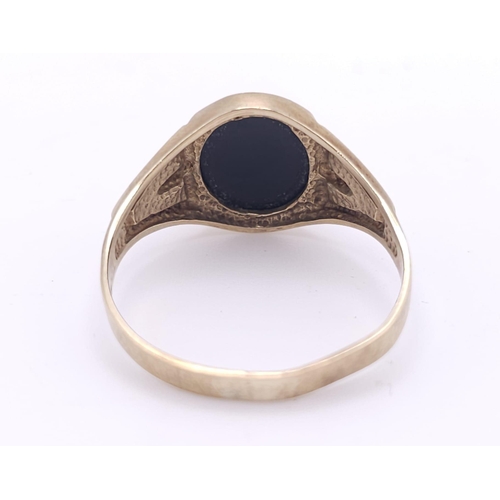 192 - A GENTS 9K GOLD OVAL BLACK ONYX RING WITH DECORATIVE SHOULDERS .   2.8gms   size U