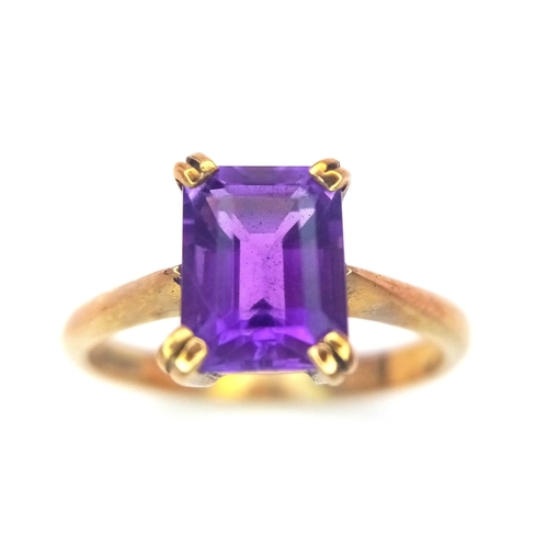 225 - A 9K GOLD RING WITH AN EMERALD CUT CENTRE AMETHYST .   2.8gms   size O