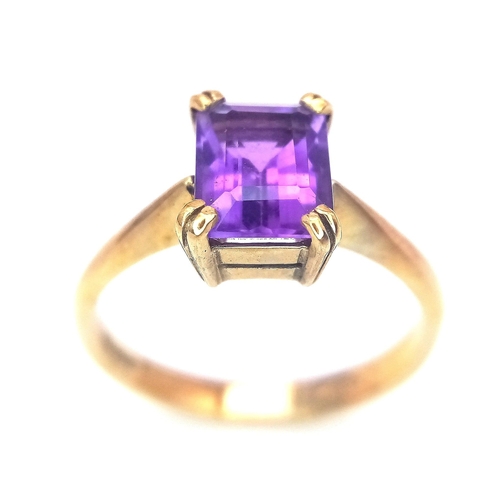 225 - A 9K GOLD RING WITH AN EMERALD CUT CENTRE AMETHYST .   2.8gms   size O