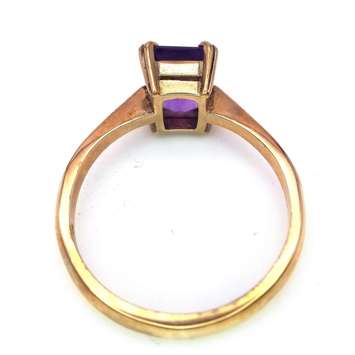 225 - A 9K GOLD RING WITH AN EMERALD CUT CENTRE AMETHYST .   2.8gms   size O