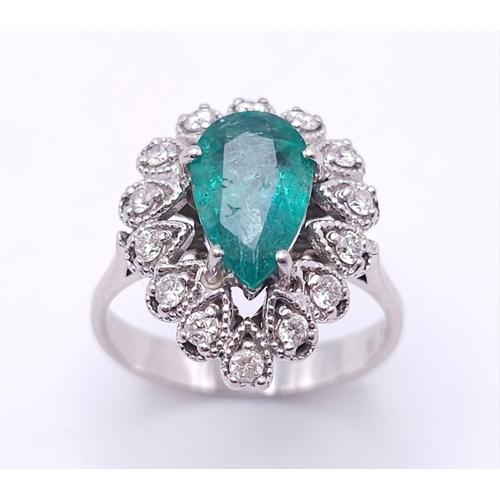 85 - An 18K White Gold Diamond and Emerald Ring. 1ct central teardrop emerald with a 1ctw brilliant round... 