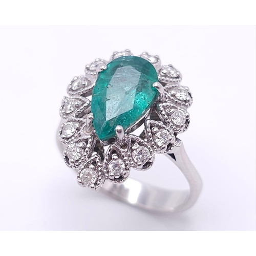 85 - An 18K White Gold Diamond and Emerald Ring. 1ct central teardrop emerald with a 1ctw brilliant round... 