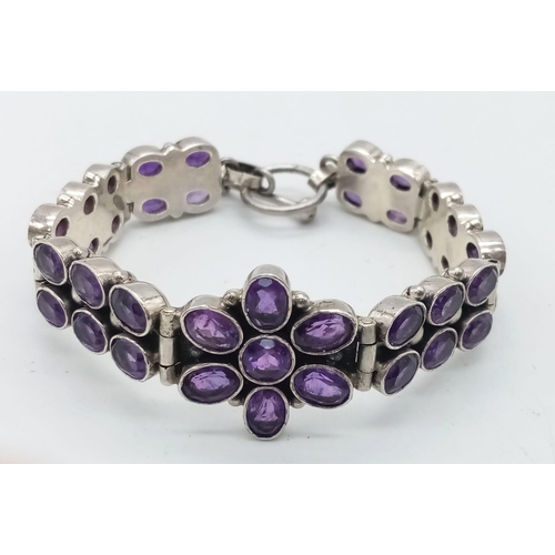 1142 - An Amethyst Tennis Bracelet set in 925 Sterling silver. Two rows of oval cut amethysts meet a centra... 