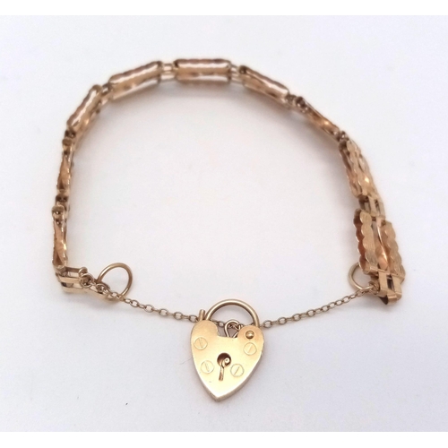 31 - AN ANTIQUE 9K GOLD NICELY PATTERNED GATE BRACELET WITH HEART PADLOCK AND SAFETY CHAIN .   8.1gms